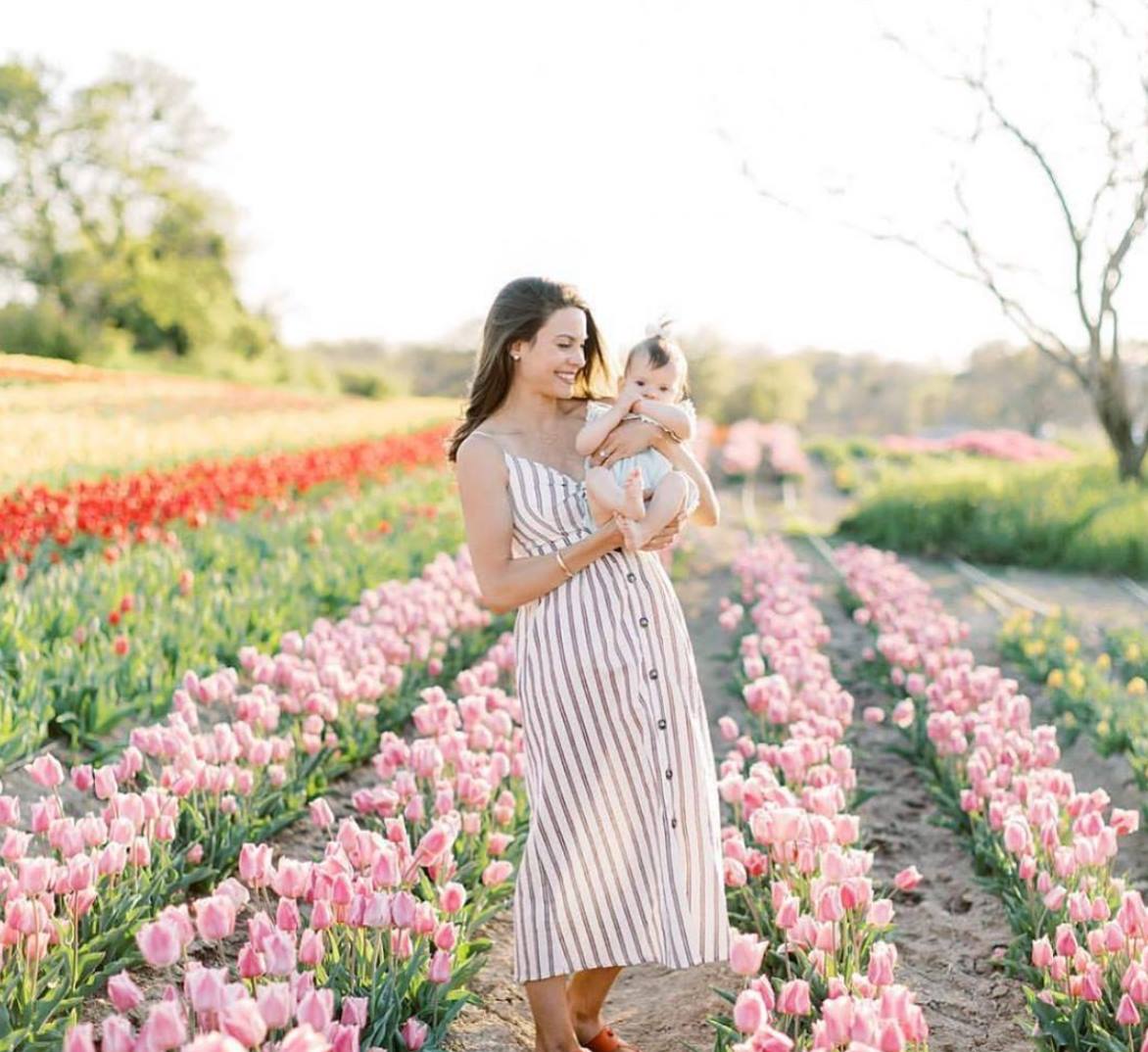 a photo of a woman holding a baby among tulips at poston gardens