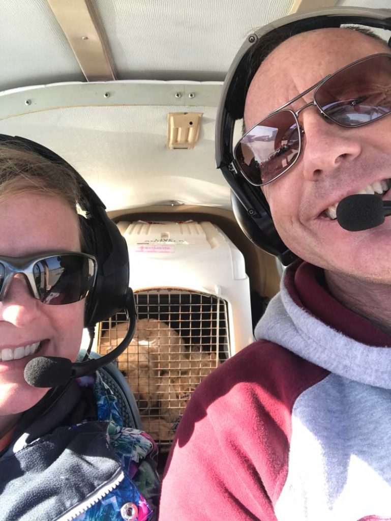 Photo of Corey and Chris Bonnell with dog inside of airplane